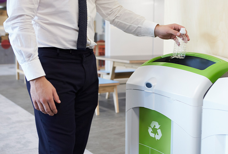 Man recycling a plastic bottle in a designated bin